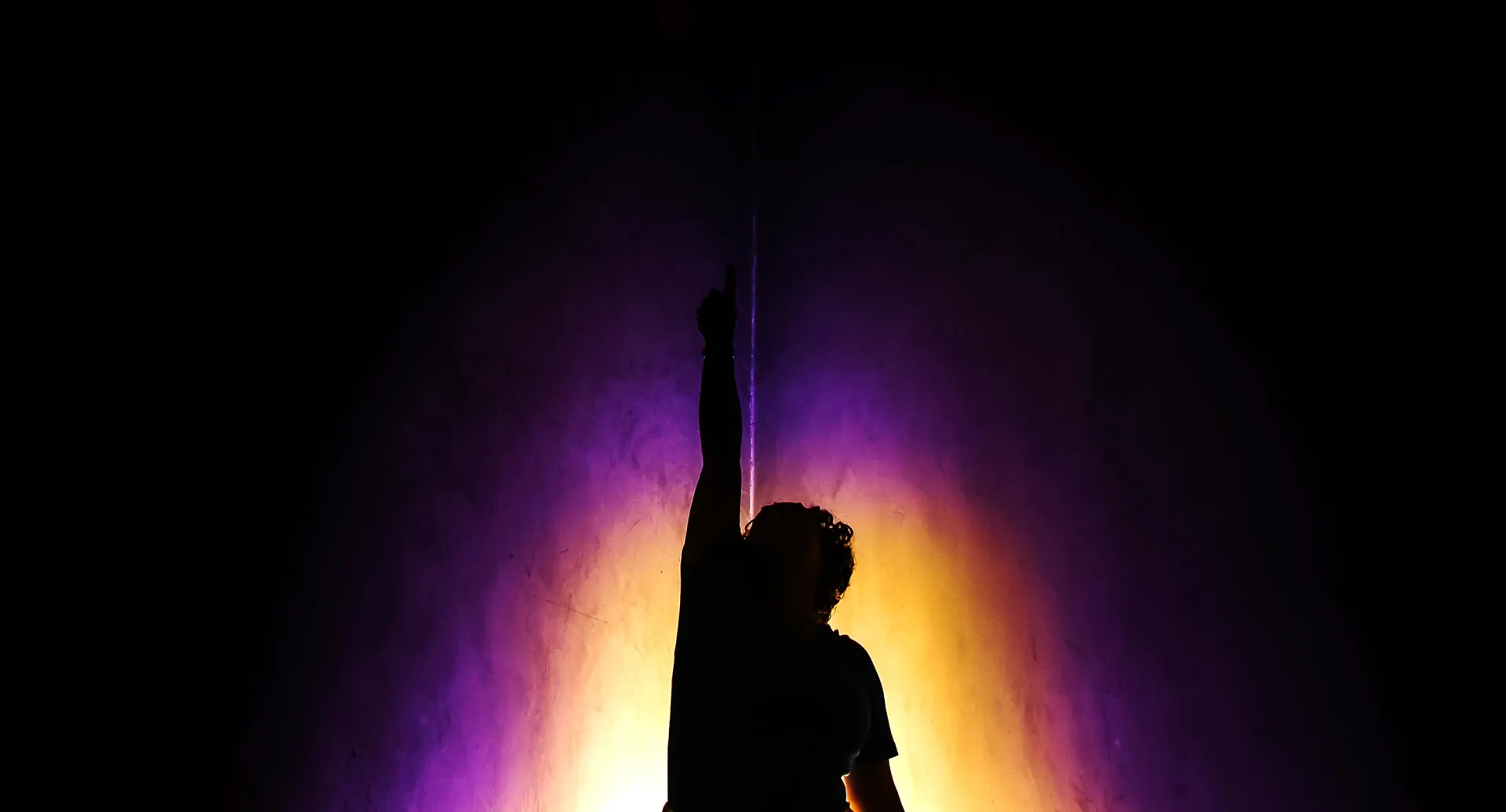 Silhueta de uma pessoa no palco, contra a luz