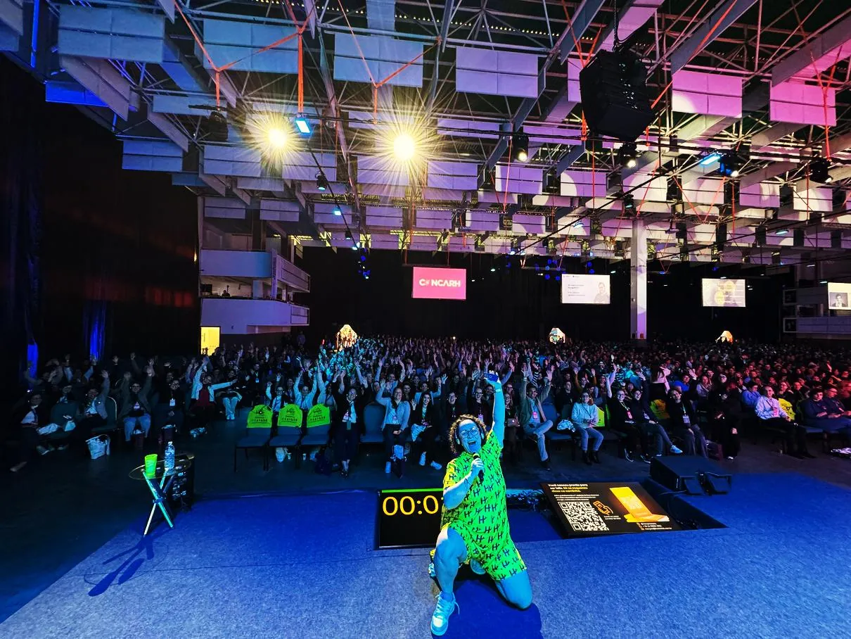 Maryana com Y no palco de uma convenção, com o auditório lotado